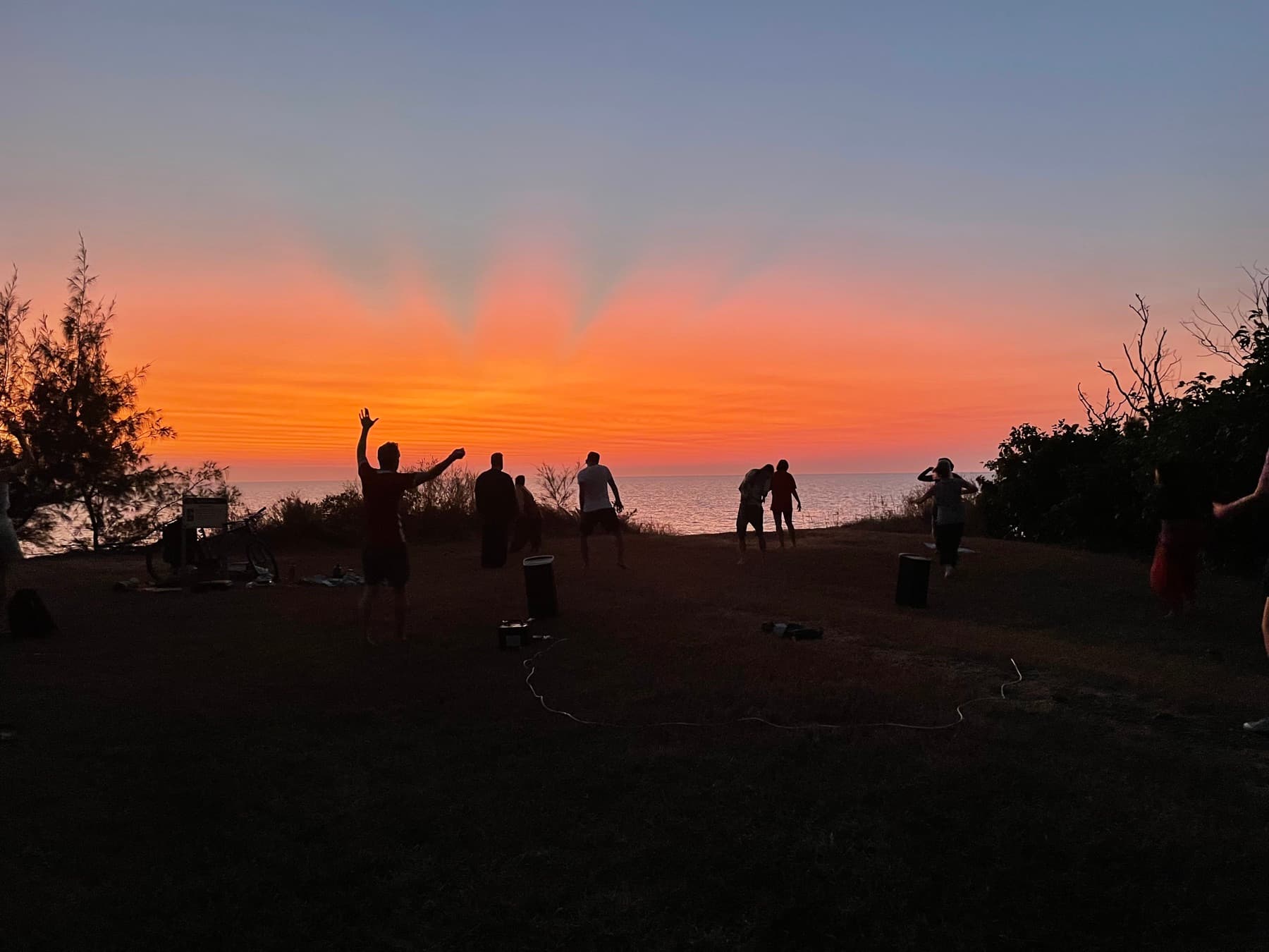 Free-dance community moving together beside the sea at sunset